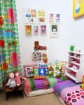 Colorful children's playroom with patterned cushions, toys, and framed art on the walls.