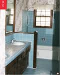 Vintage bathroom with blue tile, floral wallpaper, wooden vanity, and a window above the bathtub.