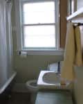 Small bathroom with clawfoot tub, shower curtain, sink, toilet, and towel on rack.