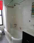 Bathroom with white subway tiles, black and white checkered floor, bathtub, shower curtain, and dark vanity.