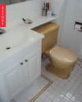 Small bathroom with beige toilet, white vanity, and tiled floor.
