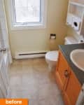 Small bathroom with beige walls, window, wooden vanity, and white toilet.