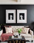 Living room with a cream sofa, patterned pillows, black wall art, and a decorative trunk table with tulips.