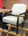 Wooden armchair with light floral upholstery on a workbench, labeled "Before."