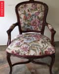 Ornate wooden chair with floral upholstery in pink, blue, and green tones.