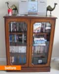 Wooden cabinet with glass doors, filled with DVDs and books, topped with a stereo and decorative camel figurines.