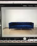 Blue velvet sofa with tufted design in a minimalist room, viewed on a computer screen in Adobe Lightroom.