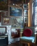Cozy corner with a blue armchair, red cushion, framed landscape art, and a Marshall amplifier.