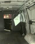 Empty interior of a white cargo van with metal partition and exposed wiring.