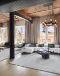 Spacious living room with white sectional sofa, wooden coffee table, large windows, and modern chandelier.