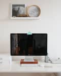 Minimalist desk setup with a computer, keyboard, white storage boxes, and a potted plant.