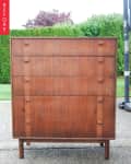 Mid-century modern wooden dresser with five drawers, set outdoors.