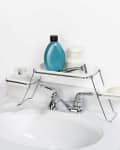 Bathroom sink with chrome faucet, shelf holding blue bottle, soap, razor, and jars.