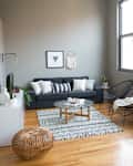 Modern living room with gray sofa, patterned rug, round coffee table, and decorative wall art.