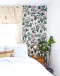 room features white bedspread with monstera print wallpaper