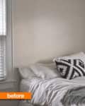 Bedroom corner with white bedding, geometric black and white pillow, and window blinds.
