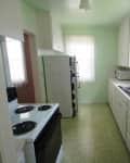Narrow kitchen with green walls, white cabinets, electric stove, and double sink, labeled "before."