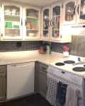 Kitchen with white cabinets, black tile backsplash, electric stove, and double sink.