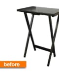 Black folding tray table with X-shaped legs and a rectangular top.