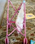 Pink toy stroller with a patterned cloth on a floral rug, surrounded by toys and a book.