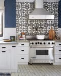 White kitchen with blue walls, patterned backsplash, farmhouse sink, and stainless steel stove.