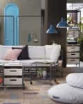 Modern living room with white sofa, blue pendant lights, bicycle on wall, and storage shelves.