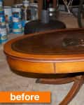 Oval wooden coffee table with a worn surface in a garage, surrounded by paint cans and bicycles.