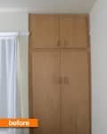 Tall wooden wardrobe with double doors next to a white curtain.