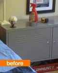 Gray metal cabinet with cleaning spray, tape, and a measuring tape on top, next to a bed and framed wall art.
