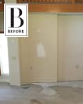 Unfinished room with patched walls, exposed concrete floor, and wooden ceiling beam.
