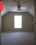 Empty room with beige walls, carpeted floor, ceiling fan, and a single window.