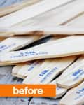 Pile of wooden paint stir sticks labeled "5 GAL" on a weathered wooden surface.
