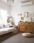 Cozy living room with a white sofa, wooden cabinet, potted plants, and decorative wall art.