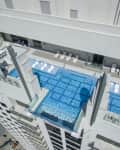 Rooftop infinity pool with lounge chairs and glass barriers on a high-rise building.