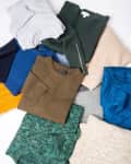 Assorted knit sweaters in various colors, including green, blue, beige, and mustard, arranged on a flat surface.