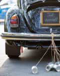 Vintage car with "Just Married" sign and tin cans tied to the bumper.