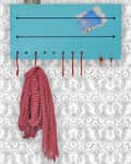 Blue wall organizer with hooks, holding a red checkered scarf, keys, and mail, against patterned wallpaper.