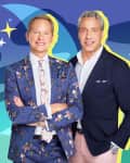 Two men in suits with floral and solid patterns, standing against a colorful abstract background with stars.