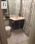 Small bathroom with white tiled floor, black vanity, white sink, and geometric shower curtain.