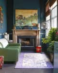 Cozy room with green sofa, fireplace, colorful painting, birdcage, and potted plant, featuring a patterned rug.