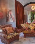 Cozy living room with floral cushions on wicker furniture, wooden doors, and a portrait on the wall.