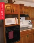 Wooden kitchen cabinets with a microwave, oven, black dishwasher, and green curtains over the sink.