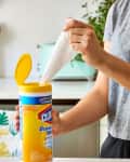 A woman in a kitchen pulling a disinfecting wipe out of its container