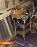 Cluttered basement corner with a metal cart, cardboard box of bottles, and electronic device.