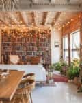 A living room with one wall covered by a large bookcase and string lights