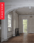 Empty room with arched doorway, chandelier, large windows, and a fireplace.