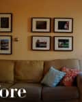 Beige sofa with colorful pillows, six framed photos on wall, and a floor lamp in a living room.