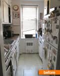 Narrow kitchen with white cabinets, fridge covered in magnets, and a window with blinds.