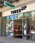 ThredUp store entrance with glass doors, mannequins, and clothing displays inside.