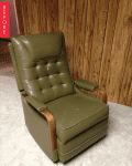 Olive green vintage recliner with wooden armrests against wood-paneled wall.